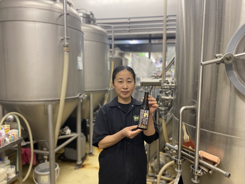 醸造所でクラフトビールを持つロコビアの鍵谷百代さん