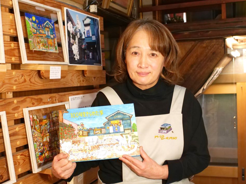 絵本「100年生きられた家」を手にする店主の佐藤真里さん