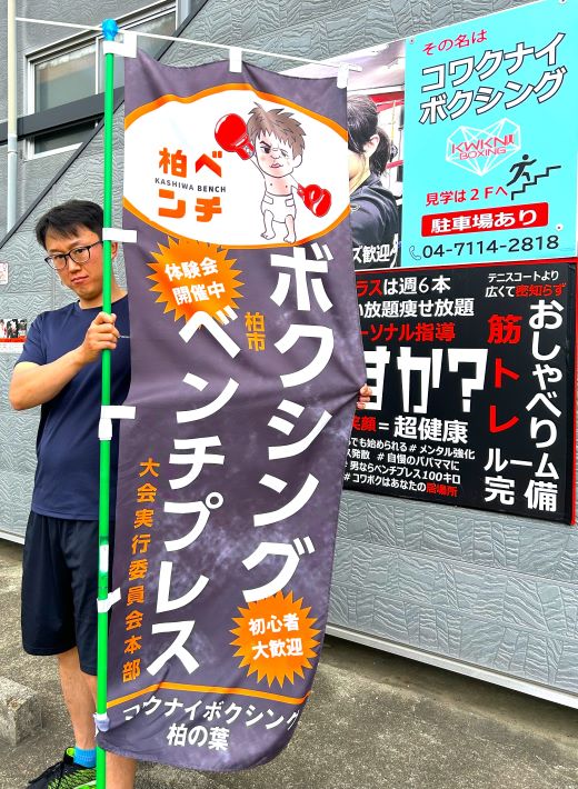 柏市ベンチプレス大会 大会本部ののぼりを広げる曲山さん