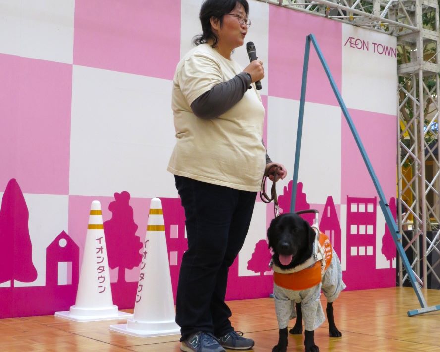 視覚障害「ロービジョン」を知る商品体験会 いばらき盲導犬協会によるデモンス トレーション。アイマスクを着けた子ど もが盲導犬と一緒に歩く体験も