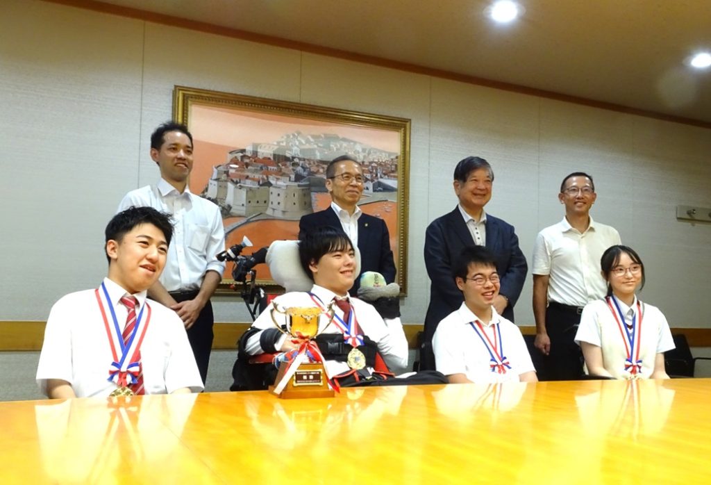 優勝報告会に出席したなっつみーズのメンバーと、(後列左から)五味翔太監督、松戸徹市長、松本淳教育長、藺牟田(いむた)明校長