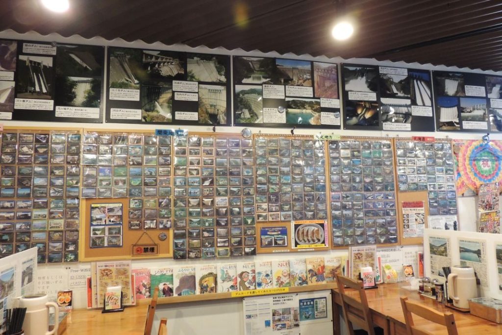 麵家西陣　店内壁一面にぎっしり貼られた日本各地のダムカード。漫画本も多数あり