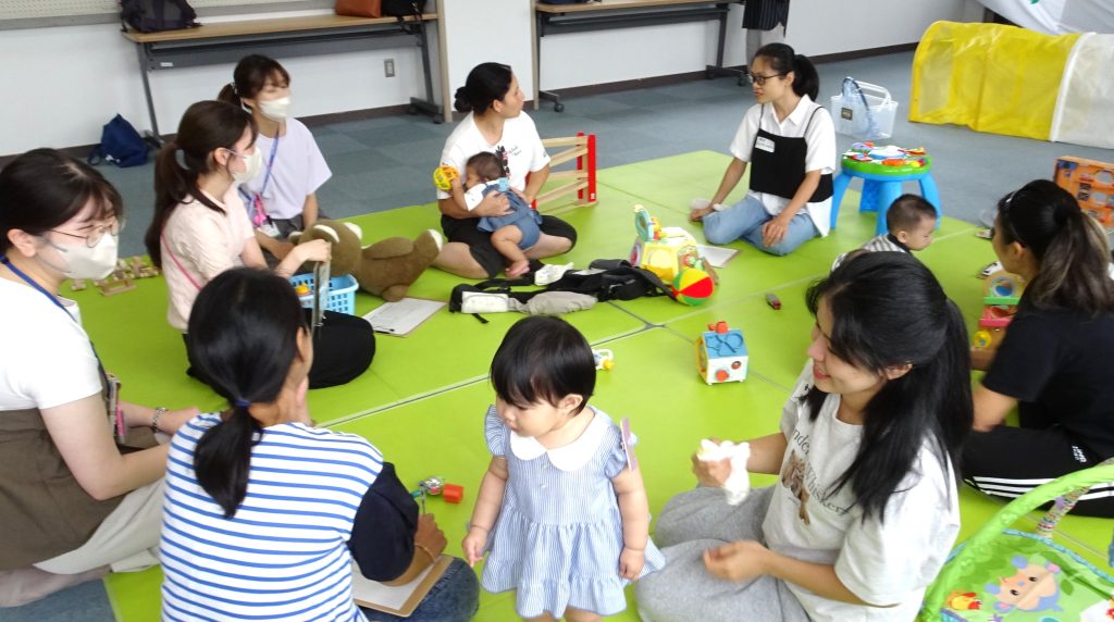 鎌ケ谷市の児童センターで外国人親子の集い 丸くなった外国人親子の間を元気に歩き回る中国の女の子