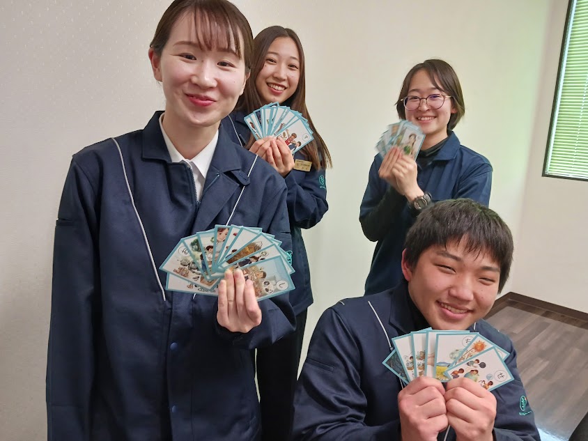 みどり産業株式会社　完成したカルタを持って笑顔の社員の皆さん